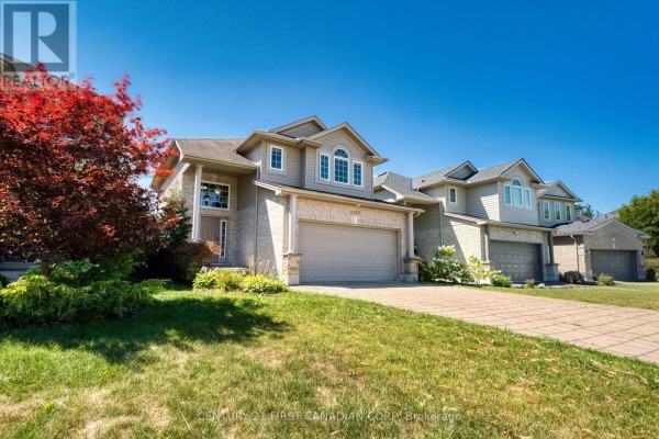 Side view of a two-story brick house with a paved driveway and green lawn. - 1197 Smither Road, London North