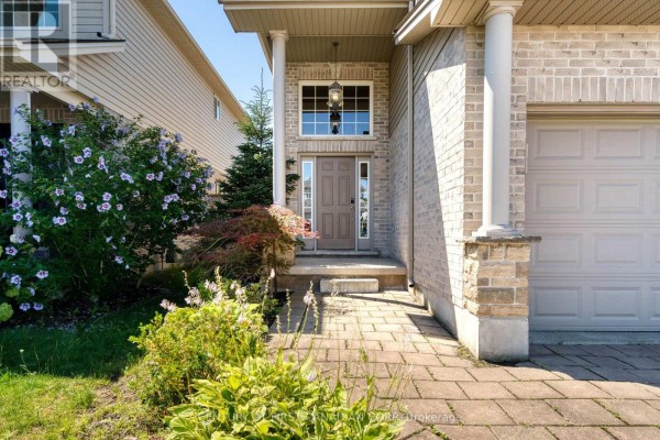 Front entrance of a house with a brown door, glass sidelights, and brick columns. - 1197 Smither Road, London North