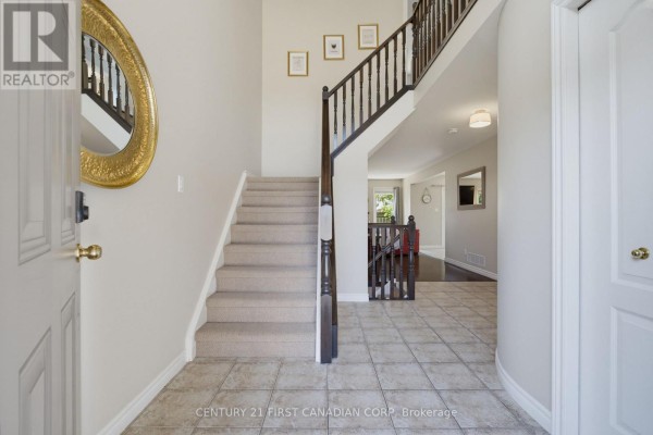 Interior entryway with a carpeted staircase, tiled floor, and a large gold mirror. - 1197 Smither Road, London North