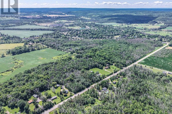 Distant aerial view of a vast wooded landscape with scattered houses and fields, with Coldwater visible. - 1197 Upper Big Chute Road, Severn