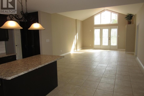 Open-concept kitchen and dining area with dark cabinetry and pendant lighting - 11981 Morris Road, Niagara Falls