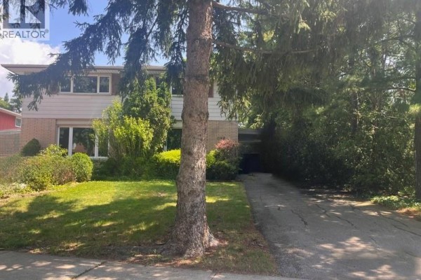 View of a house exterior with beige siding, brick, and a driveway. - 1199 Nottingham Avenue, Burlington
