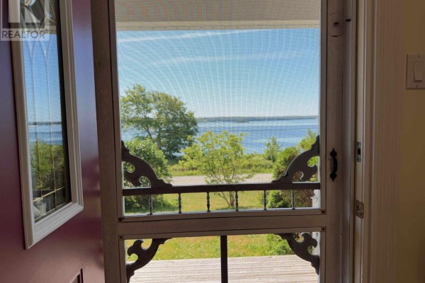 View of a calm blue body of water and green trees through a screen door. - 1199 Raynardton Road, Raynardton