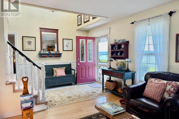 Foyer with a dark blue bench, red door, staircase, and wood floors. - 1199 Raynardton Road, Raynardton