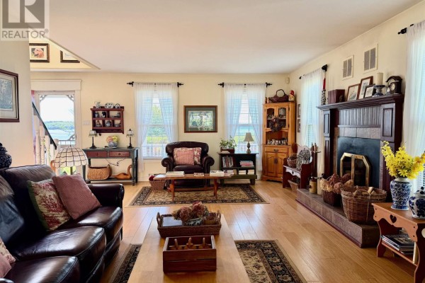 Living room with leather sofas, fireplace, wood floors, and light curtains. - 1199 Raynardton Road, Raynardton