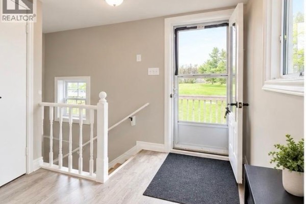 Entryway with a screen door, staircase, and view of the backyard and trees. - 1199 Route 133 Road, Grand Barachois