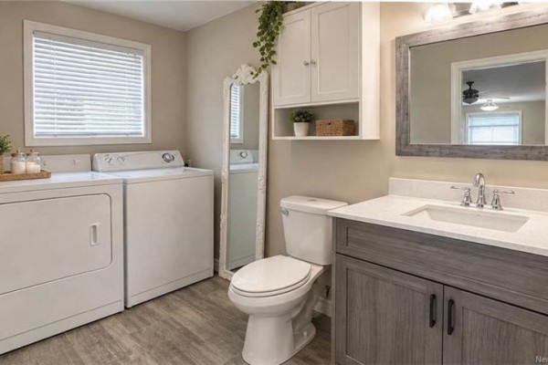 Bathroom with a white toilet, stacked washer and dryer, and a gray vanity with a white countertop. - 1199 Route 133 Road, Grand Barachois