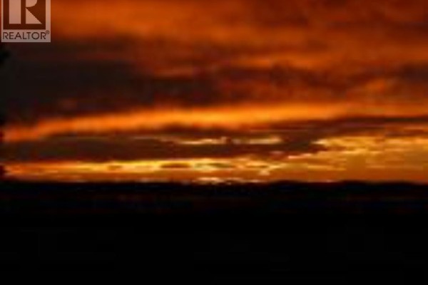 Dramatic orange and red clouds fill the sky during a sunset over a dark landscape. - 12, 420069 Range Road 284, Rural Ponoka County