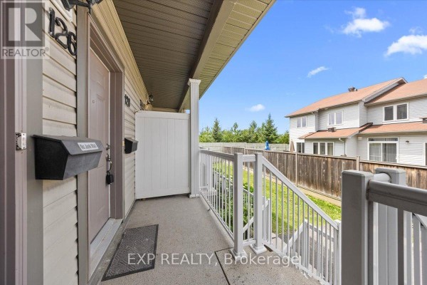 Close-up of an apartment entrance with beige siding, a beige door numbered 126, and a white railing. - 12 - 128 Sternes Private, Ottawa