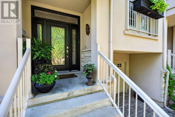 Close-up of a modern townhouse entrance with a black glass door and white railings. - 12 - 1335 Ontario Street, Burlington