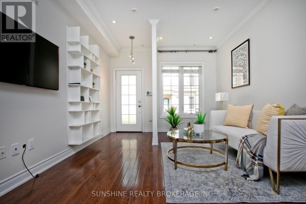 Living room with white built-in shelves, hardwood floors, and a glass coffee table. - 12 - 20 Hargrave Lane, Toronto