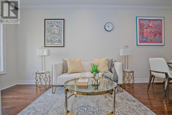 Living room with a white sofa, gold accents, framed art, and a wall clock. - 12 - 20 Hargrave Lane, Toronto