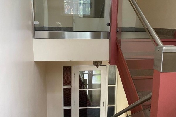 Top of a staircase with red risers, glass railing, and a frosted glass door below. - 12 - 2675 Bloor Street W, Toronto