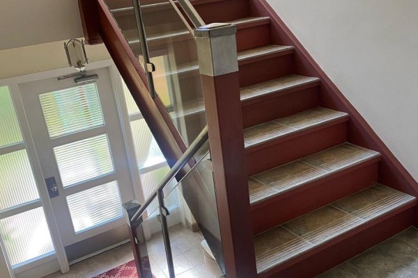 View looking down a staircase with red risers, tiled treads, and a frosted glass door. - 12 - 2675 Bloor Street W, Toronto