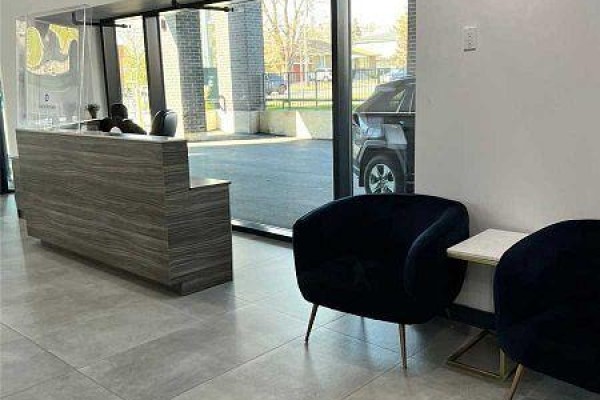 Building lobby with a grey wood reception desk, velvet chairs, and glass entrance doors. - 12 - 3237 Bayview Avenue, Toronto
