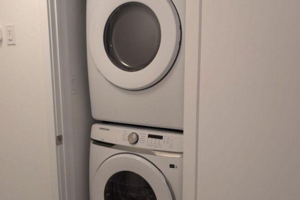 Stacked white Samsung washer and dryer set in a small closet with a closed door. - 12 - 42 Lowes Road W, Guelph
