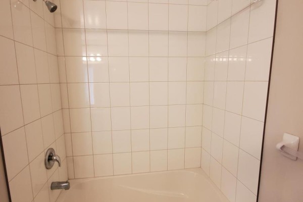 White tiled shower and bathtub in a bathroom with a shower head. - 12 - 50 Pinnacle Drive, Kitchener