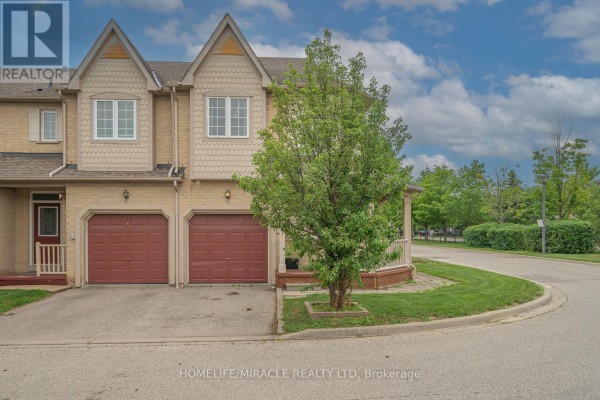 Side view of a townhouse featuring a red double garage door and a covered porch. - 12 - 7284 Bellshire Gate, Mississauga