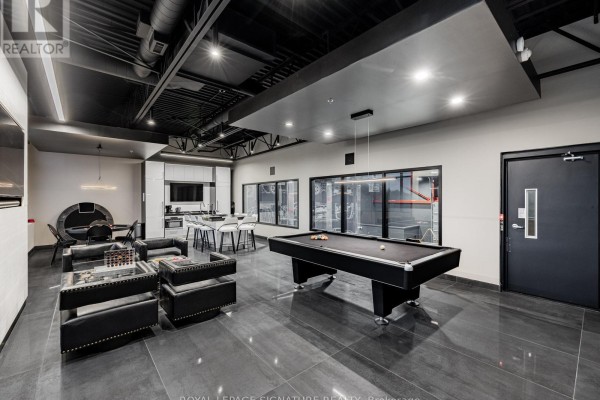Interior common area with a pool table, seating, and kitchenette against a dark ceiling. - 12 - 760 Laurentian Drive, Burlington