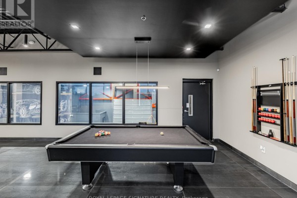 Recreation room with a pool table, billiard cues on the wall, and modern lighting fixtures. - 12 - 760 Laurentian Drive, Burlington
