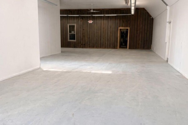 Empty interior of a commercial space with white walls and wood-paneled section. - 12 - 8021 35 Highway, Kawartha Lakes