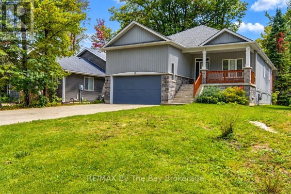 Side exterior view of a grey house with a blue garage door and green lawn. - 12 51 Street S, Wasaga Beach