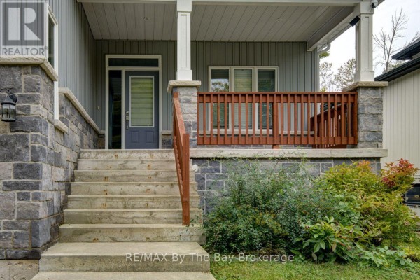 Close-up of concrete stairs leading to a covered front porch with a wooden railing. - 12 51 Street S, Wasaga Beach