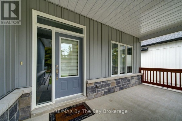 View of the covered front porch, grey front door, and large windows. - 12 51 Street S, Wasaga Beach