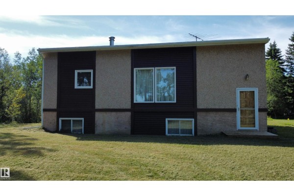 Exterior of a house with brown and beige siding, small windows, and a wooden front door. - #12 53220 Rge Road 15, Rural Parkland County