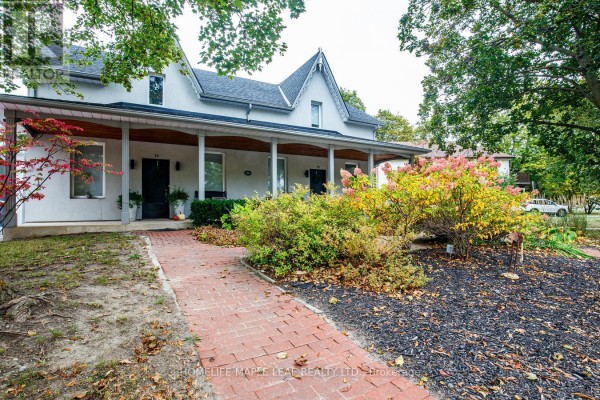 View of the house facade with multiple entrances, a covered porch, and brick pathway. - 12 Adamson Street N, Halton Hills