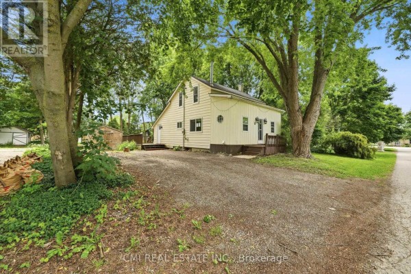 A pale yellow house with a covered porch surrounded by lush green trees. - 12 Argyle Street, Kincardine