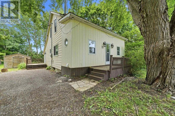 Close-up of the pale yellow house entrance with a wooden deck and stone pathway. - 12 Argyle Street, Kincardine
