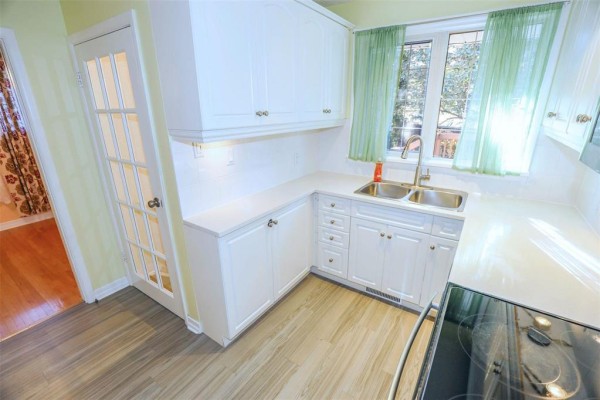 Another view of the kitchen showing white cabinets, dual sinks, and wooden flooring. - 12 Barberry Road, Winnipeg
