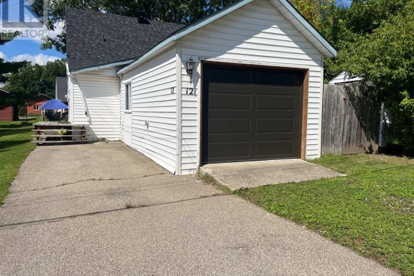 Side view of a white sided bungalow with a mature tree in the front yard. - 12 Churchill Crescent, Smiths Falls