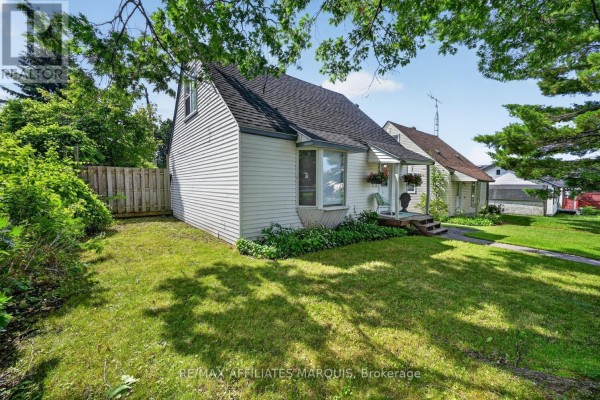 A white bungalow with white siding, a covered front porch, and a green lawn. - 12 Churchill Crescent, Smiths Falls