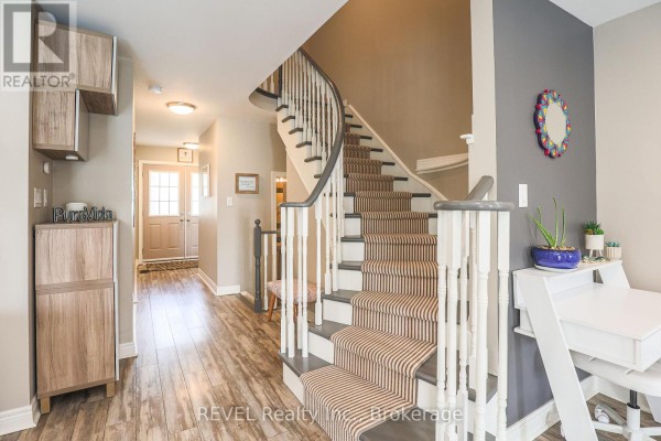 Interior view of a townhouse staircase with striped runner and gray walls. - 12 Colonel Lyall Street, St  Catharines