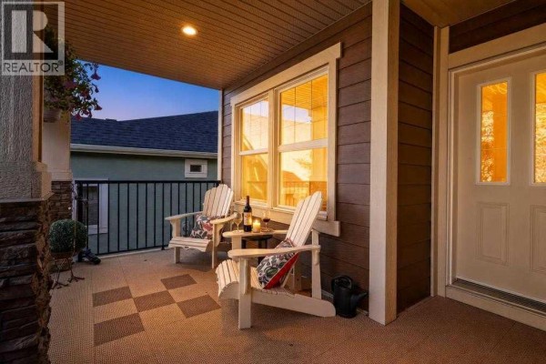 Covered front porch with two Adirondack chairs, a small table, and a view of the street. - 12 Crestridge Rise Sw, Calgary