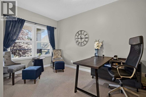 Home office with a large desk, executive chair, sitting area, and a view of the backyard. - 12 Crestridge Rise Sw, Calgary