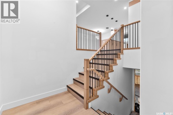 Wooden staircase with black metal spindles and a light wood floor leading to the upper level. - 12 Elkwood Cove, Dundurn Rm No  314