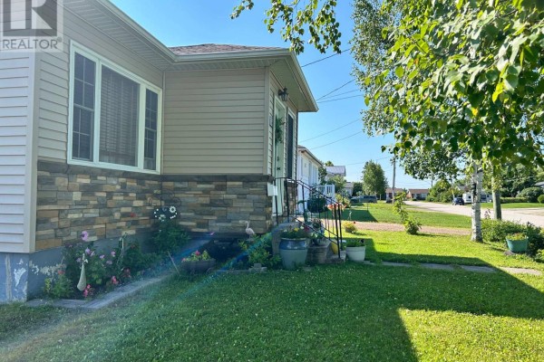 Close-up of the front entrance and side of a house with stone and beige siding. - 12 Erickson Avenue, Kapuskasing