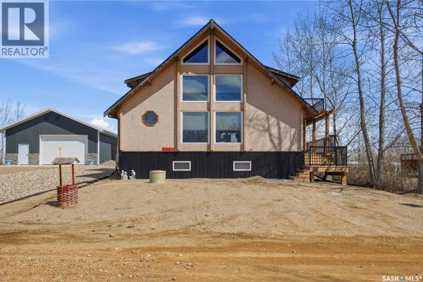 Front view of a beige house with a steep A-frame roof, large windows, and a small circular window. - 12 Finch Crescent, Thomson Lake
