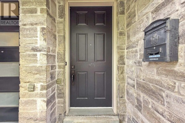 Black front door with stone surround and black mailbox on townhouse. - 12 Gala Lane, Toronto