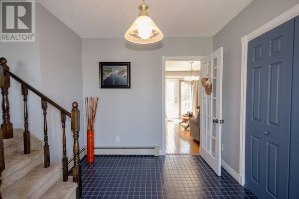 Foyer with blue tiled floor, carpeted stairs, and double glass doors. - 12 Hancott's Lane, Frederickton