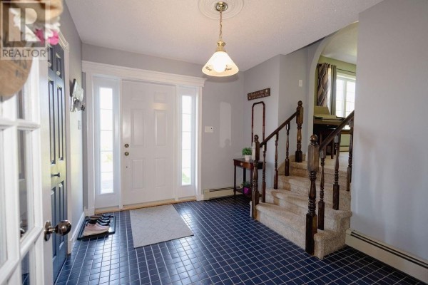 Entrance foyer with white double doors, grey walls, and carpeted staircase. - 12 Hancott's Lane, Frederickton