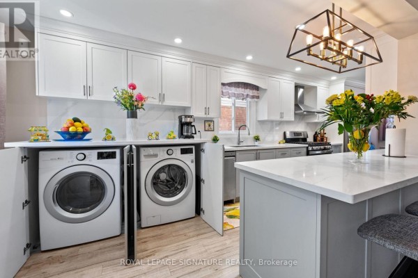 Kitchen with white and grey cabinets, stainless steel appliances, and a white island with pendant lighting. - 12 Hewitt Crescent, Ajax