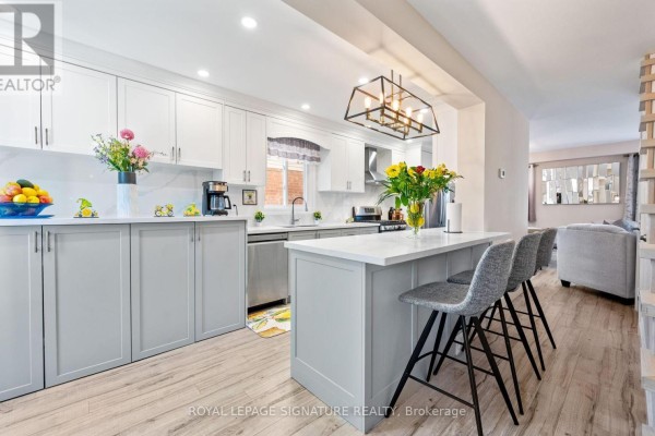 Kitchen with white and grey cabinets, stainless steel appliances, and a white island with pendant lighting. - 12 Hewitt Crescent, Ajax