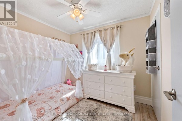 Child's bedroom with a canopy bed, white dresser, unicorn decor, and beige curtains. - 12 Hewitt Crescent, Ajax