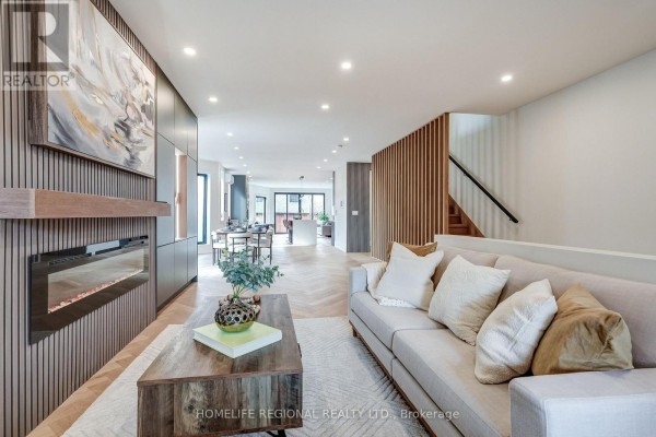 Spacious living area featuring a sofa, fireplace, and dining space - 12 Macdonell Avenue, Toronto