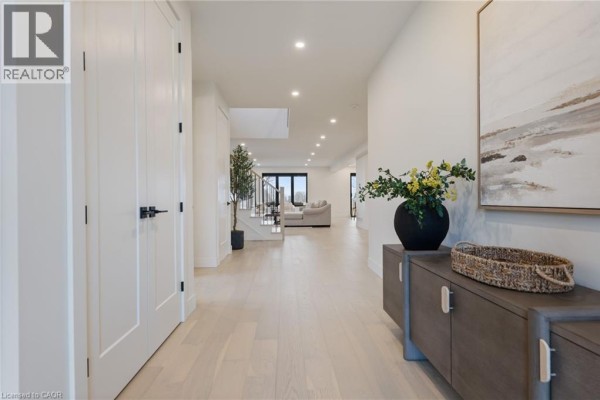 Bright foyer with double doors, light wood flooring, and decorative plant - 12 Macneil Court, Port Burwell