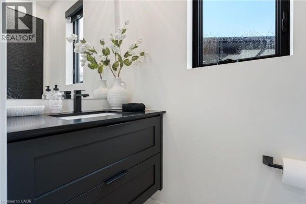 Stylish bathroom featuring black cabinetry, white sink, and window with natural light - 12 Macneil Court, Port Burwell